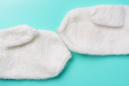 White woolen mittens on a turquoise backgroundの写真素材