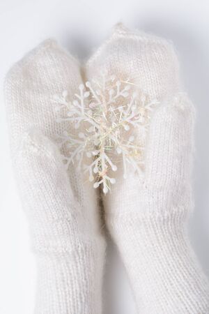 White woolen mittens with a Christmas toy on a white backgroundの写真素材