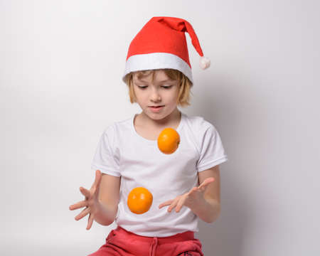 Little girl in santa hat juggling tangerinesの写真素材