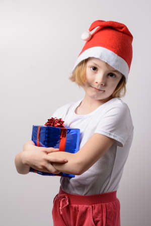 Little girl in santa hat with Christmas giftsの写真素材