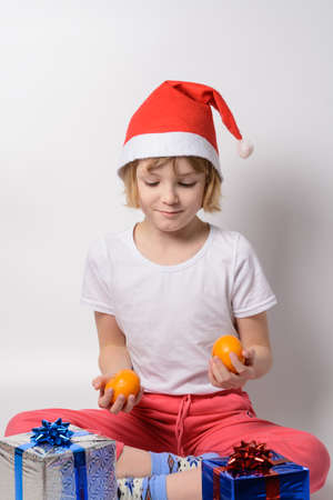 Little girl in santa hat juggling tangerinesの写真素材