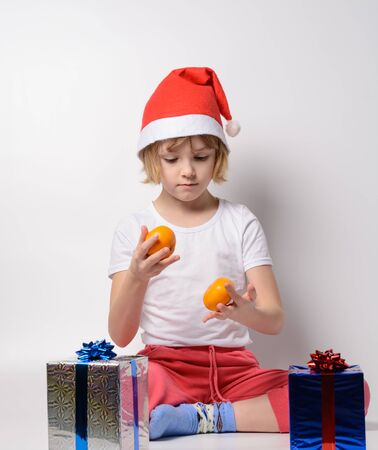 Little girl in santa hat juggling tangerinesの写真素材