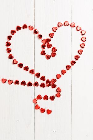 The figure in the shape of a heart made of red string on the wooden tableの写真素材