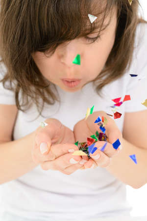 Young woman blows colorful confetti from his handsの写真素材