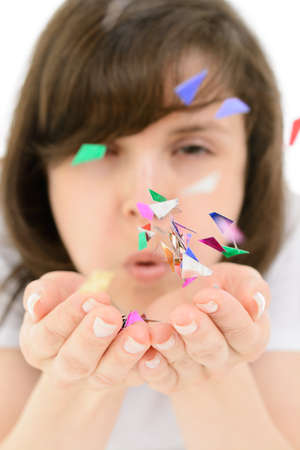 Young woman blows colorful confetti from his handsの写真素材