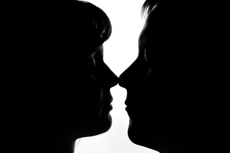 Black and white silhouettes of couples in love during a kissの写真素材