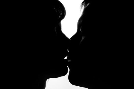 Black and white silhouettes of couples in love during a kissの写真素材