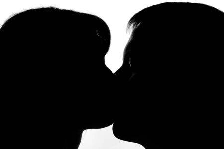 Black and white silhouettes of couples in love during a kissの写真素材