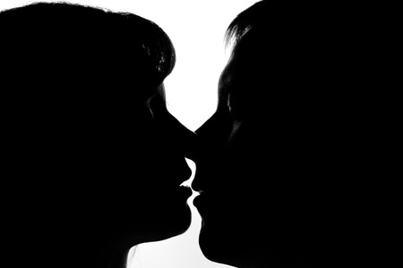 Black and white silhouettes of couples in love during a kissの写真素材