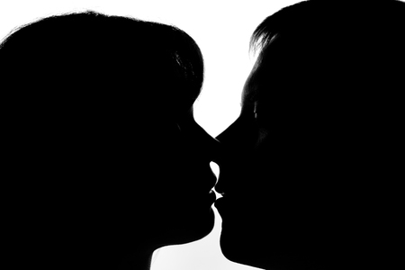 Black and white silhouettes of couples in love during a kissの写真素材