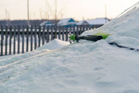 Green cleaning brush snow on the hood of carの写真素材