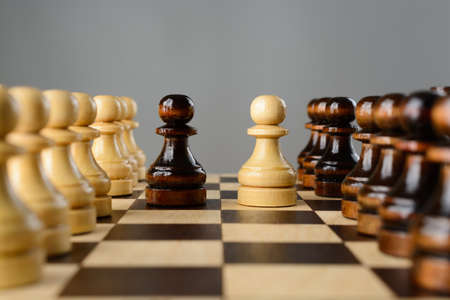 Black and white pawns facing each other on a chessboard