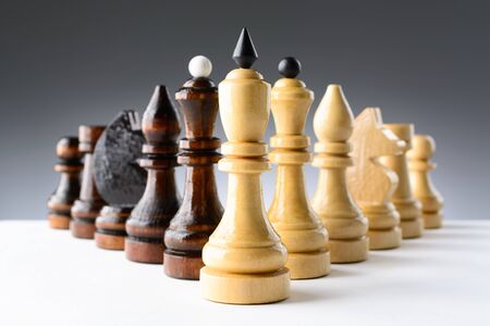 Black and white chess pieces on a white table on the gradient backgroundの写真素材