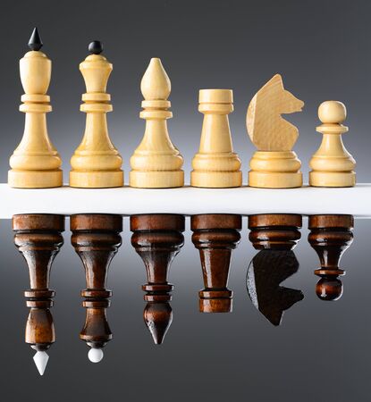 Black and white chess pieces on a white table on the gradient backgroundの写真素材