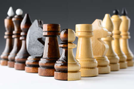Black and white chess pieces on a white table on the gradient backgroundの写真素材