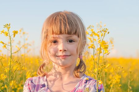 Girl with blond hair in a field of yellow flowersの写真素材