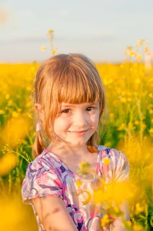 Girl with blond hair in a field of yellow flowersの写真素材