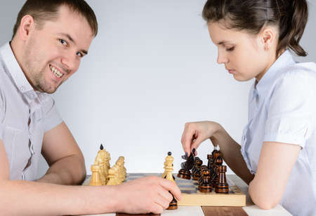 Girl playing against men and was going to go black pawn in chessの写真素材