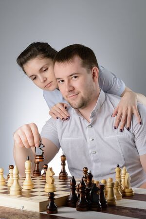 Woman standing behind and watching men playing chessの写真素材