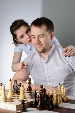 The woman tells the man's ear how to play chessの写真素材