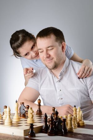 The woman tells the man's ear how to play chessの写真素材