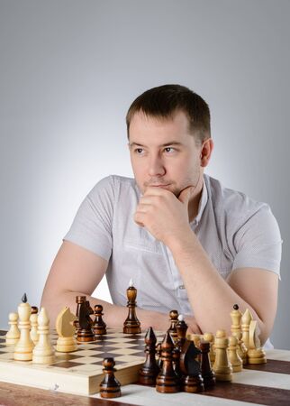 Man in white shirt thinking of the game of chessの写真素材