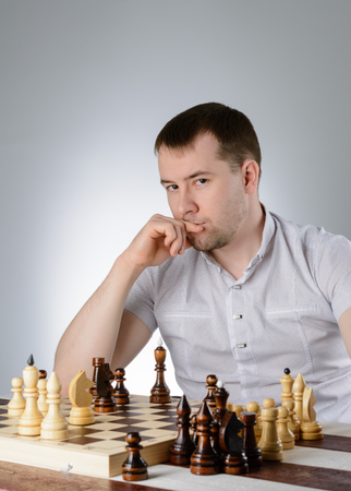 Man in white shirt thinking of the game of chessの写真素材