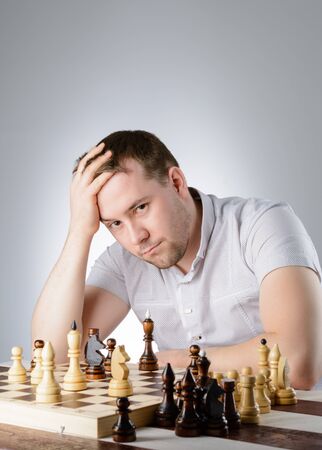 Man in white shirt thinking of the game of chessの写真素材