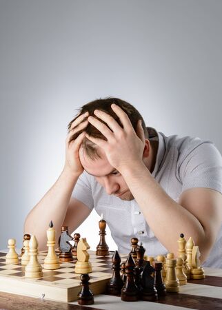 Man in white shirt thinking of the game of chessの写真素材