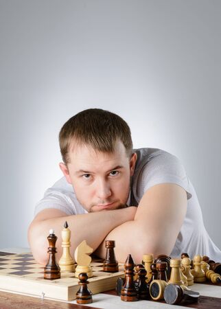 The man put his head on his folded hands on the chessboardの写真素材