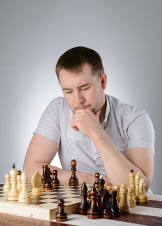 Man in white shirt thinking of the game of chessの写真素材