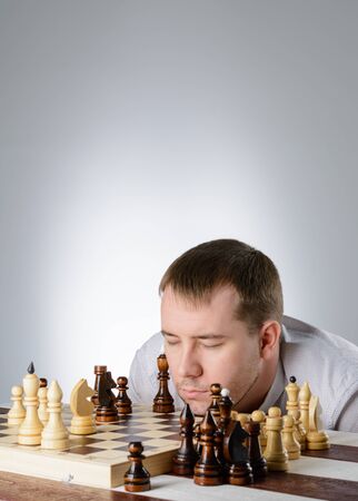 Man in white shirt thinking of the game of chessの写真素材