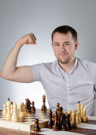 A man in a white shirt shows the power in the game of chessの写真素材