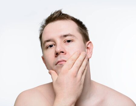 Naked man stroking his face after shaving