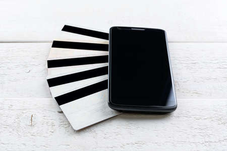 Credit cards and smartphone lying on a white wooden tableの写真素材