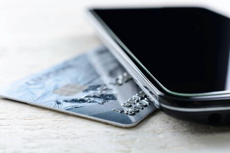 Credit card and smartphone lying on a white wooden tableの写真素材