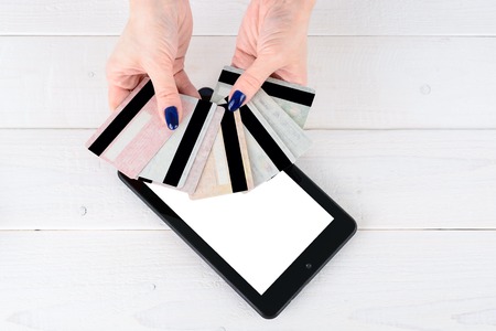 A woman holds credit cards in a fan shape on a smartphoneの写真素材