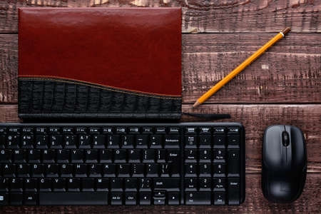 Top view on a wooden table office worker: keyboard, mouse, pen, notebookの写真素材