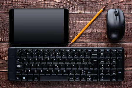 Top view on a wooden table office worker: keyboard, mouse, pen, a tabletの写真素材