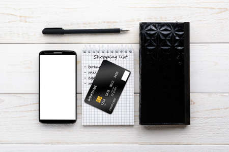 Smartphone, notebook, pen and credit card on a white wooden tableの写真素材