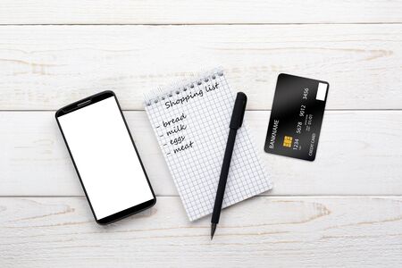Smartphone, notebook, pen and credit card on a white wooden tableの写真素材