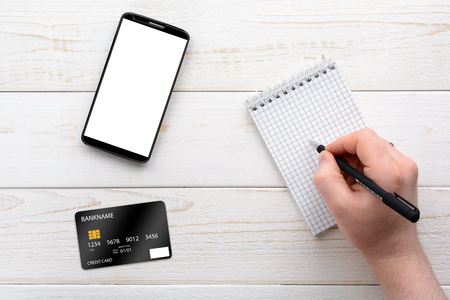 Smartphone, notebook, pen and credit card on a white wooden tableの写真素材