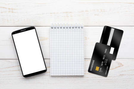Smartphone, notebook and credit card on a white wooden tableの写真素材