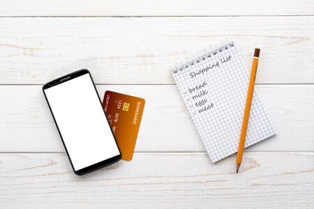 Smartphone, notebook, pencil and credit card on a white wooden tableの写真素材