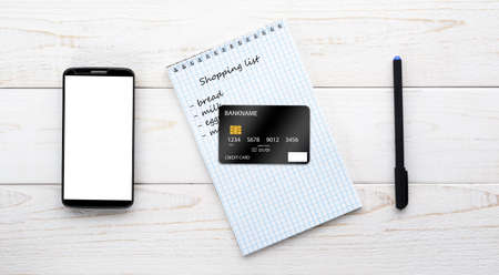 Smartphone, notebook, pen and credit card on a white wooden tableの写真素材