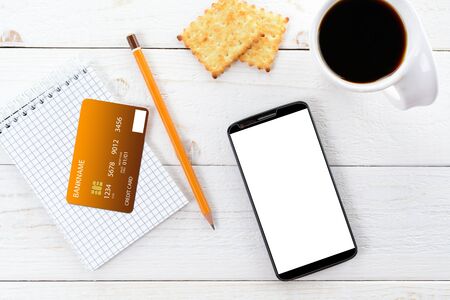 Smartphone, notebook, pencil and credit card on a white wooden tableの写真素材