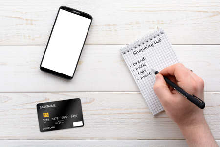 Smartphone, notebook, pen and credit card on a white wooden tableの写真素材