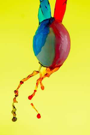 White egg doused with paint on a yellow background