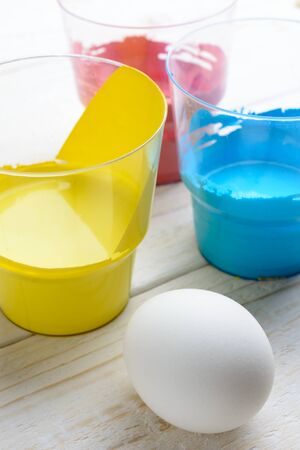 Chicken eggs and paint lie on a white wooden tableの写真素材