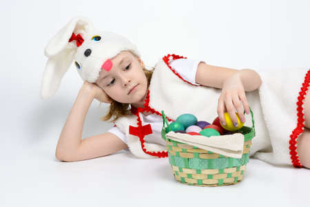 Girl in rabbit costume with a basket of Easter eggs on a white backgroundの写真素材